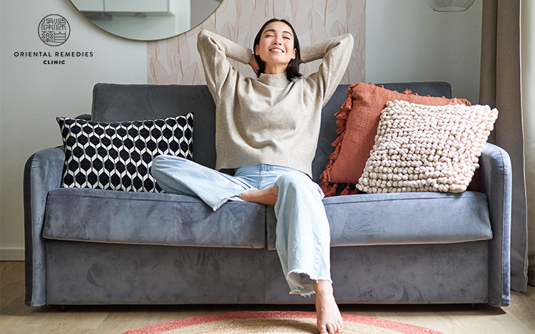 Relaxed young asian woman enjoying rest on comfortable sofa at home