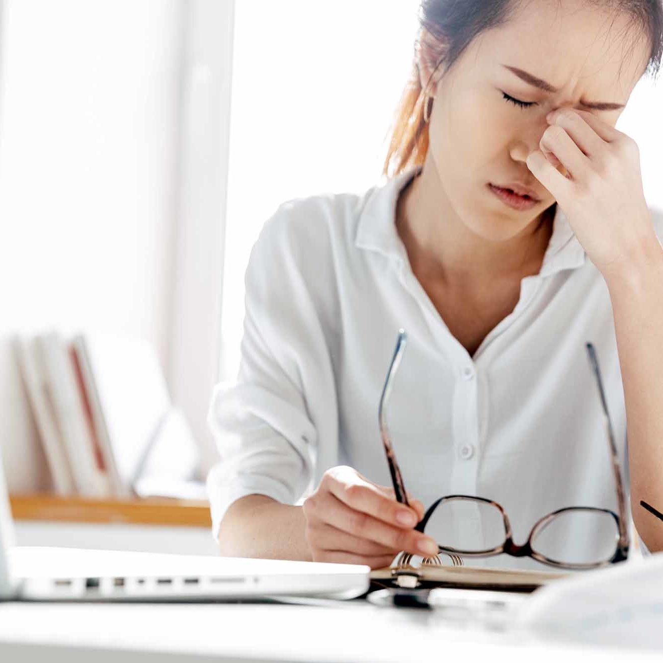Tired asian business woman sitting with closed eyes and touching Tired asian business woman sitting with closed eyes and touching it in office