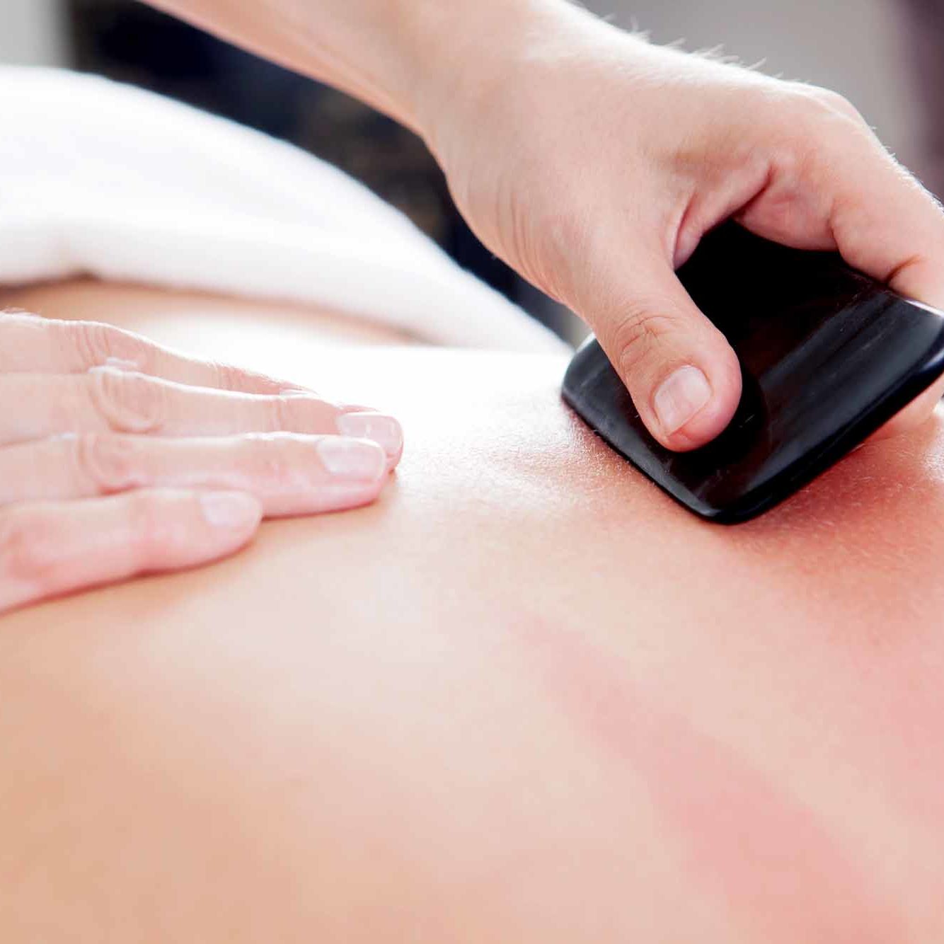 Large bone scraper tool being used ruing a guasha acupuncture treatment