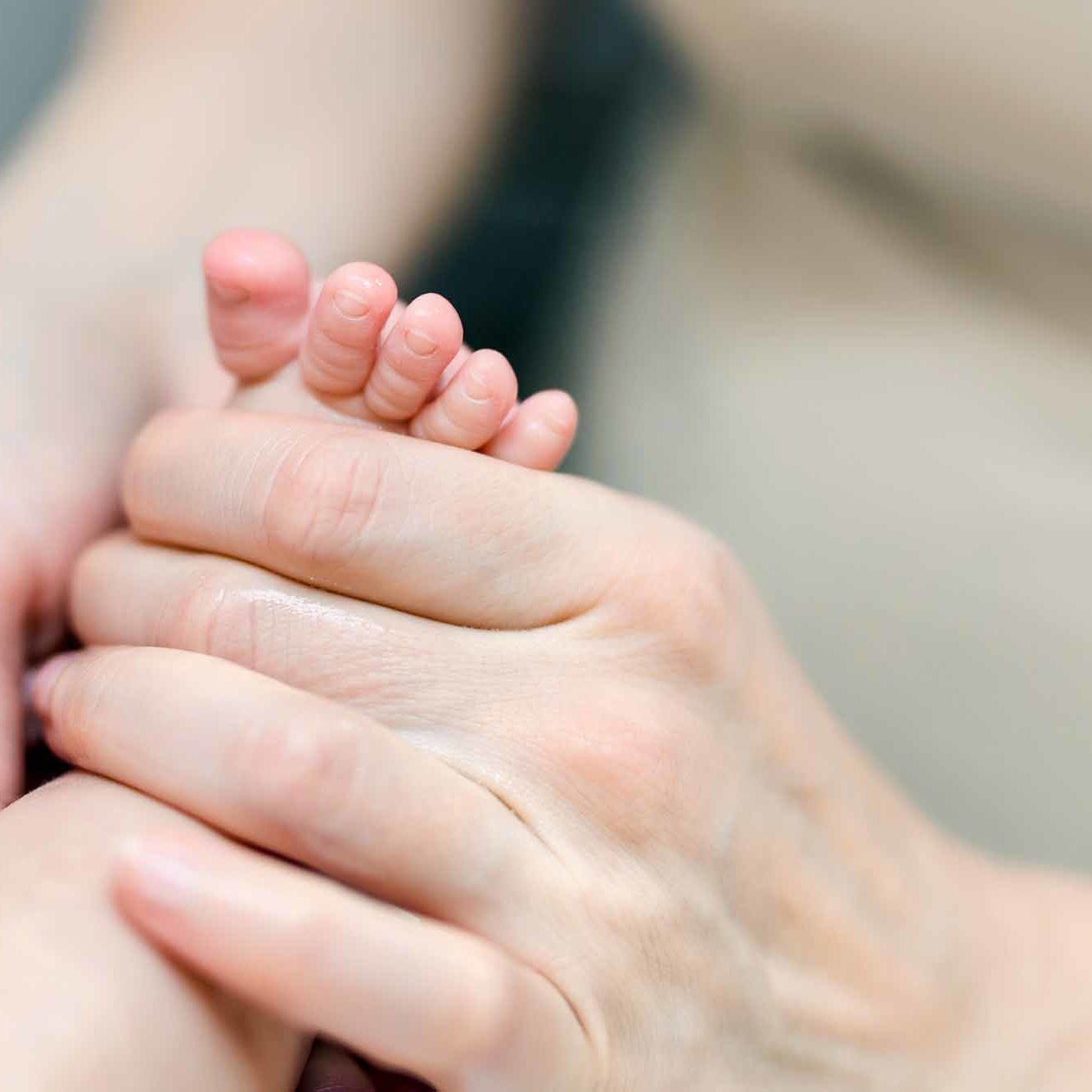 Mother making feet massage for infant baby. Parent care about kid. Children health car and disease prevention.