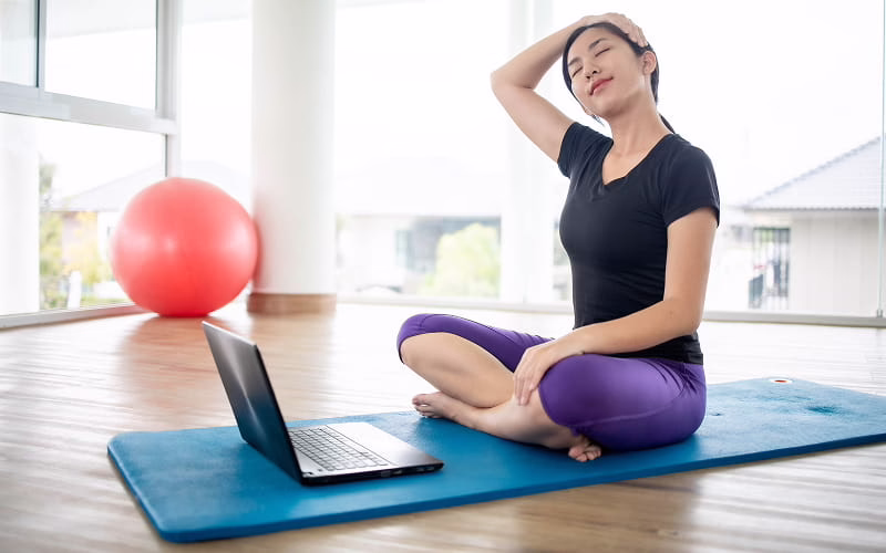 a woman doing at home yoga to reduce neck pain